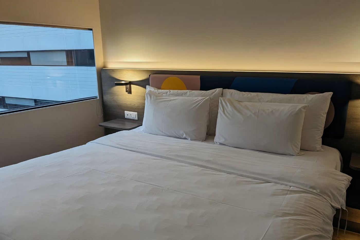Lit d'hôtel aux oreillers blancs sous une lumière chaude