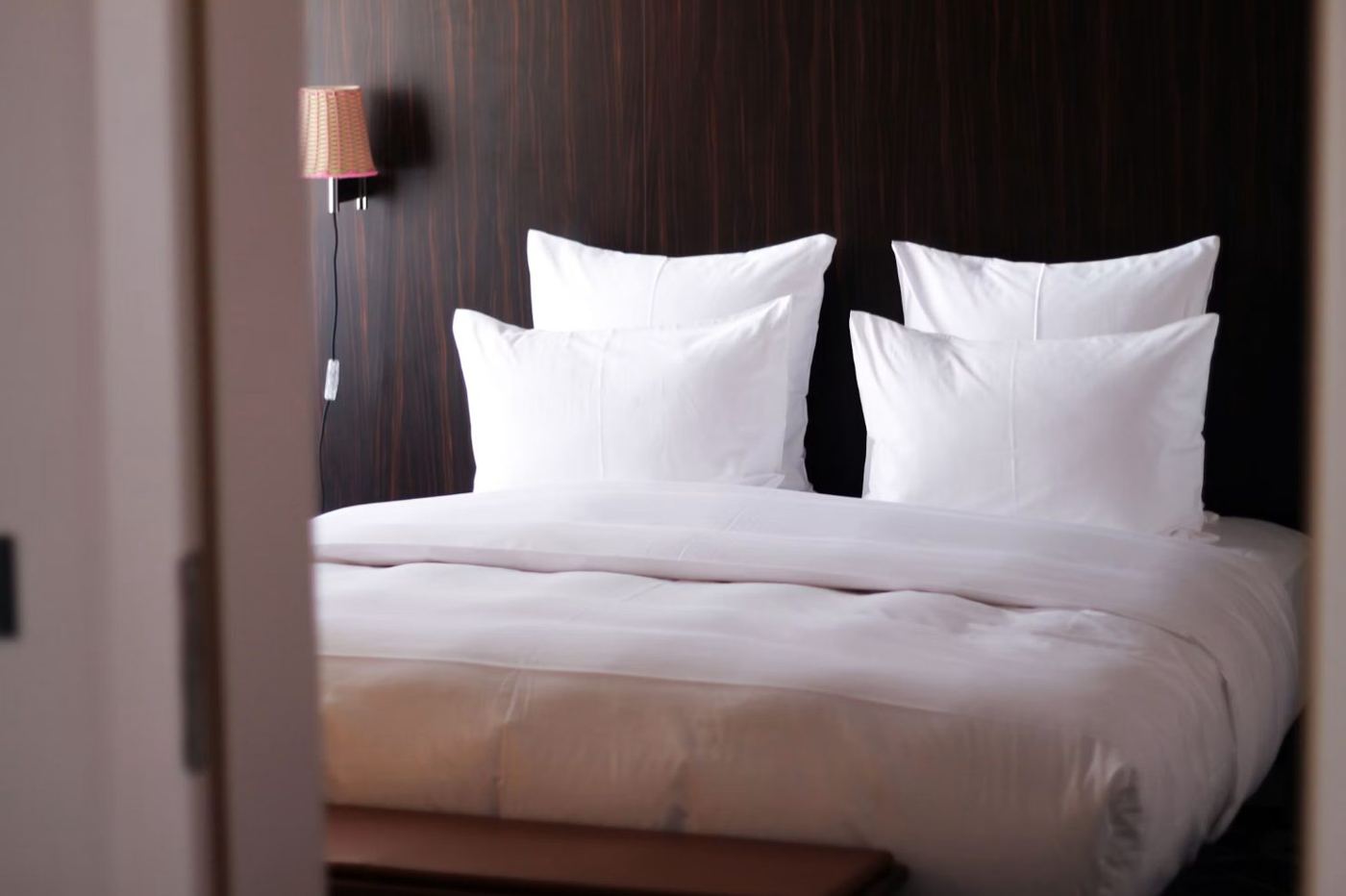 Oreillers blancs sur un lit d'hôtel, tête de lit en bois sombre